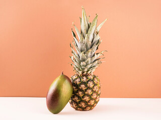 Ripe pineapples with mangoes, balancing fruit on a colored background. Food levitation concept