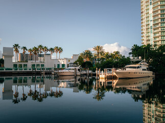 Obraz premium horizontal landscape beautiful blue sky white clouds reflections water house building boat marina florida palms trees reflections sun