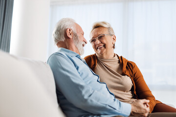 Happy mature couple sitting on sofa and communicating