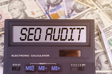 On the table are dollars and a calculator on the electronic board which says SEO AUDIT