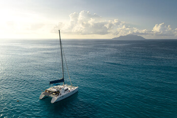 Eco yacht catamaran sailing in ocean at sunset. Aerial view - obrazy, fototapety, plakaty