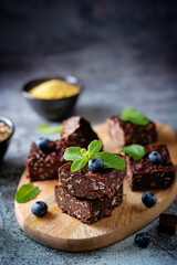 Dark chocolate oats millet porridge brownies decorated with blueberries and mint leaves