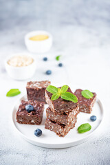 Dark chocolate oats millet porridge brownies decorated with blueberries and mint leaves