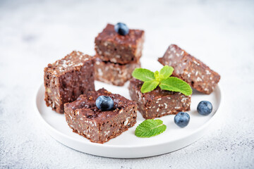 Dark chocolate oats millet porridge brownies decorated with blueberries and mint leaves