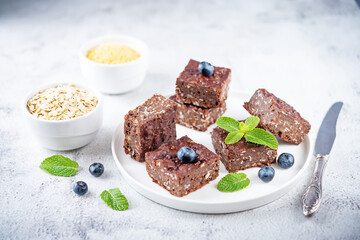 Dark chocolate oats millet porridge brownies decorated with blueberries and mint leaves