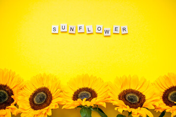 inscription from wooden blocks sunflower. Bright juicy sunflowers on a bright yellow background. Layout. Flat lay.