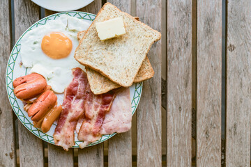Closeup of a breakfast plate with bread, eggs, bacon and fruit.