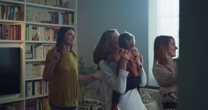 Cinematic shot of carefree happy family members of different generation are having fun listening to the music and dancing crazy in living room at home. Concept of celebration, happiness, fun, family.