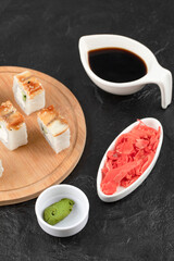 Sushi rolls with eel on wooden board with soy sauce and ginger