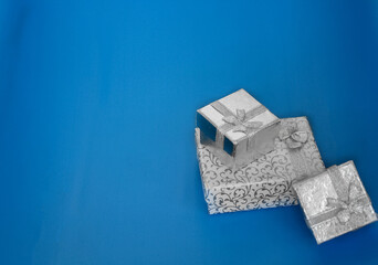 3 silver gift boxes on the blue background. silver jewelry boxes with copy space