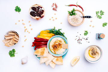Various bowls of homemade hummus and Baba ghanoush. Traditional hummus with thyme, olive oil and paprika, vegetables, pomegranate, herbs, pita and crisp bread. Middle Eastern authentic Arabic cuisine.