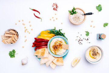 Various bowls of homemade hummus and Baba ghanoush. Traditional hummus with thyme, olive oil and paprika, vegetables, herbs, pita and crisp bread. Middle Eastern authentic Arabic cuisine.