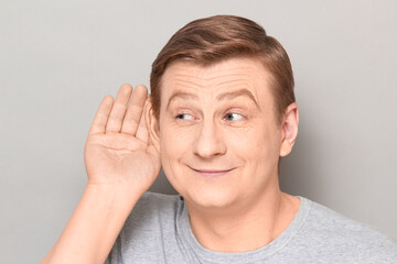 Portrait of happy man placing hand near ear and eavesdropping