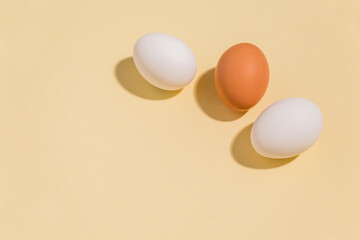 Chicken eggs on a beige background with close-up shadows, enough space to copy. Minimalism
