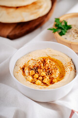 Hummus in a bowl and pita on a light table. Mediterranean appetizer, vegetarian healthy food concept. Top view, flat lay, copy space.