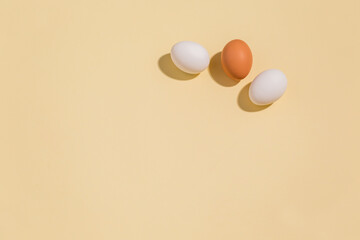 Three chicken eggs on a beige background, enough space to copy. Minimalism with shadows. Preparation for Easter