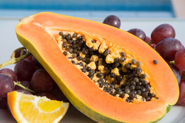 cut exotic papaya and red grapes in the sun natural fruit close-up
