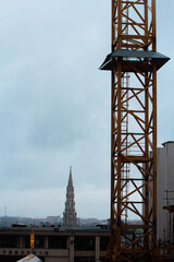 Torre de catedral en Bruselas sobre un cielo nublado y una grúa industrial (Bélgica)