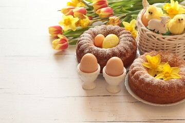 Wielkanocne tło z pisankami, ciastami, koszyczkiem i wiosennymi kwiatami