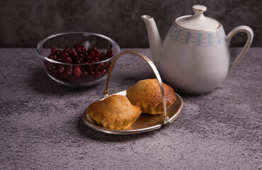 The concept of a homemade tea party with muffins. A teapot and a plate of muffins on a dark background