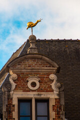Escultura dorada de un caracol en la azotea de un edificio clásico belga