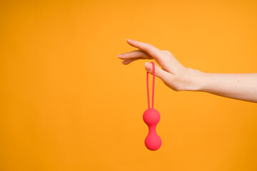 Female hand with vaginal Kegel balls or sex toy for adults to achieve female orgasm. Maintaining vaginal muscle tone and pelvic health