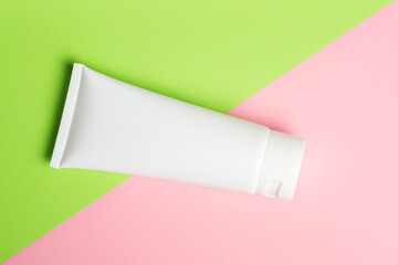 White plastic tube with face, hand and body cream, on light green paper. Sun protection lotion, sunscreen. Summer skin care concept with spf flat lay. mockup