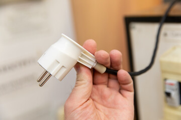 The plug of an electrical appliance for supplying voltage in a person's hand.