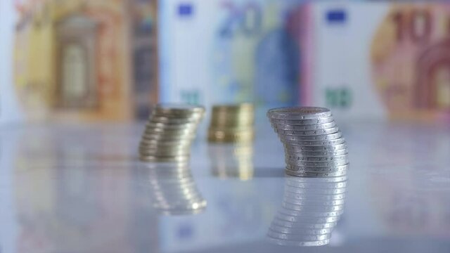 Growing pile of euro coins with backdrop of euro bills. Time lapse.