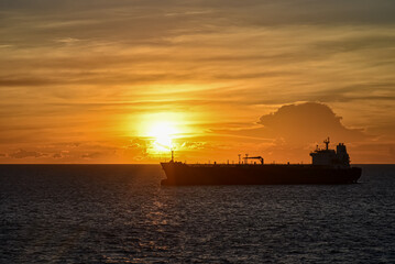 Silhouette of the cargo ship on a beautiful sunset background.