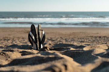 Flip flops stuck in the sand. Concept of beach vacation and relaxation.