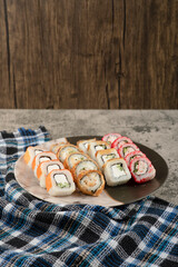 Plate of various delicious sushi rolls on marble table