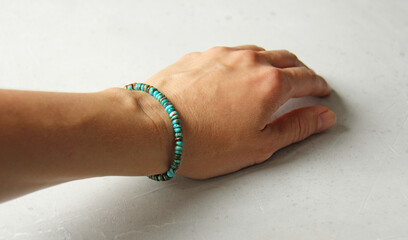 Turquoise bracelet. A bracelet made of stones on a hand from a natural stone Turquoise. Bracelet made of natural stones. Handmade jewelry. Handmade bracelets on light modern background