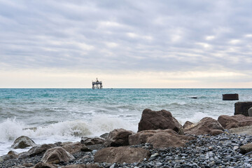 winter beach with seascape and a rickety structure on the stilts of an aquaculture farm in the distance
