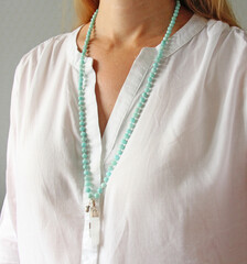 Rosary mala 108 beads from natural stones mint amazonite are worn on a girl in a white shirt. Author's jewelry from natural stones, Buddhism, matra, prayer, rosary from stones for prayer and beauty