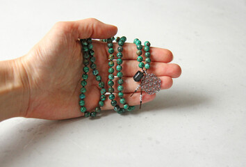 Rosary mala 108 beads from natural stones Chrysocolla lie in girl's hand. Author's jewelry from natural stones, Buddhism, matra, prayer, rosary from stones for prayer and beauty. Rosary in hand