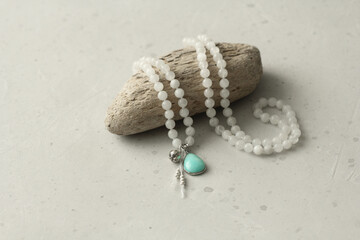 Rosary mala 108 beads from natural stones Moonstone lie on light modern background. Author's jewelry from natural stones, Buddhism, matra, prayer, rosary from stones for prayer, beauty. Long beads