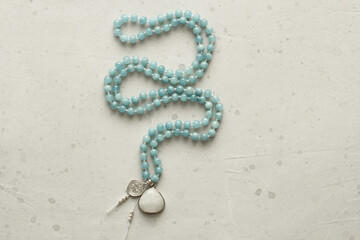 Rosary mala 108 beads from natural stones aquamarine lie on light modern background. Author's jewelry from natural stones, Buddhism, matra, prayer, rosary from stones for prayer, beauty. Long beads