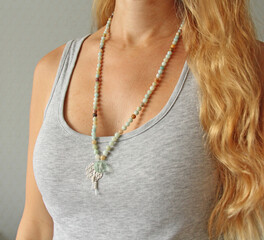 Rosary mala 108 beads from natural stones mint amazonite are worn on a girl in a grey shirt. Author's jewelry from natural stones, Buddhism, matra, prayer, rosary from stones for prayer and beauty