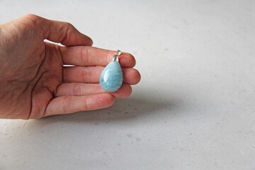 A pendant made of natural stone aquamarine silver lies on a woman's hand. Author's jewelry from natural stones. Designer jewelry. On a light modern background. Natural minerals
