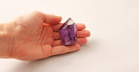 Natural amethyst stone is on a woman's hand, in the palm of her hand, on a light background. Natural stones, crystals for magic, lithotherapy, geology, minerals, stone collection