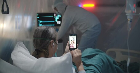 Senior woman patient lying in hospital bed talking online with family on smartphone during isolation - Powered by Adobe