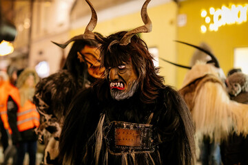 Krampus night parade, People in scary fur costumes and masks with hornes walk on the street, Traditional show before Christmas, historical street Getreidegasse, Salzburg, Austria