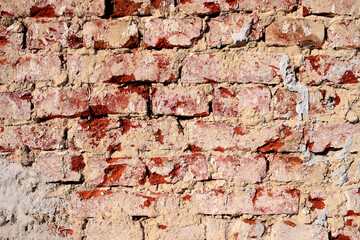 Dilapidated red brick wall stained with plaster. A background with a dilapidated red cloth texture 