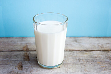 Milk in a glass on a wooden table. Fresh milk