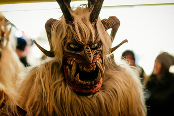 Krampus night parade, People in scary fur costumes and masks with hornes walk on the street,...