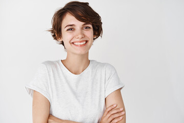 Close-up of happy professional girl cross arms on chest, smiling at camera, white background