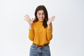 Wow super. Excited brunette girl jumping and clapping hands from excitement and joy, staring down...