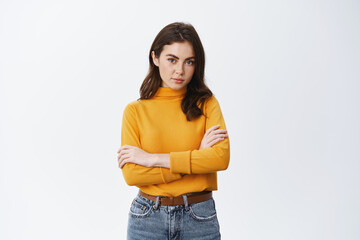 Confident young woman cross arms on chest and staring at camera like professional, standing...