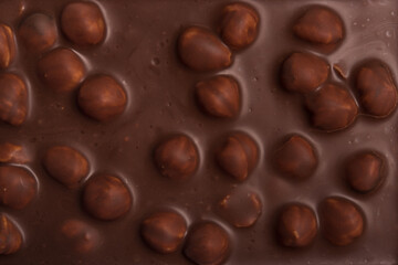 Milk chocolate with hazelnuts, sweet cocoa dessert. Chocolate texture or background.
